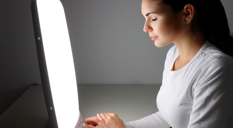 A woman basking the glow of a light therapy device